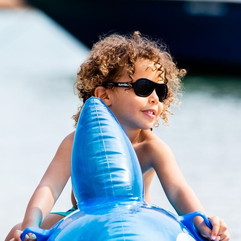 Child wearing black sunglasses on a water inflatable
