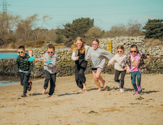 six children wearing sunnies children's polarised sunglasses running along the beach