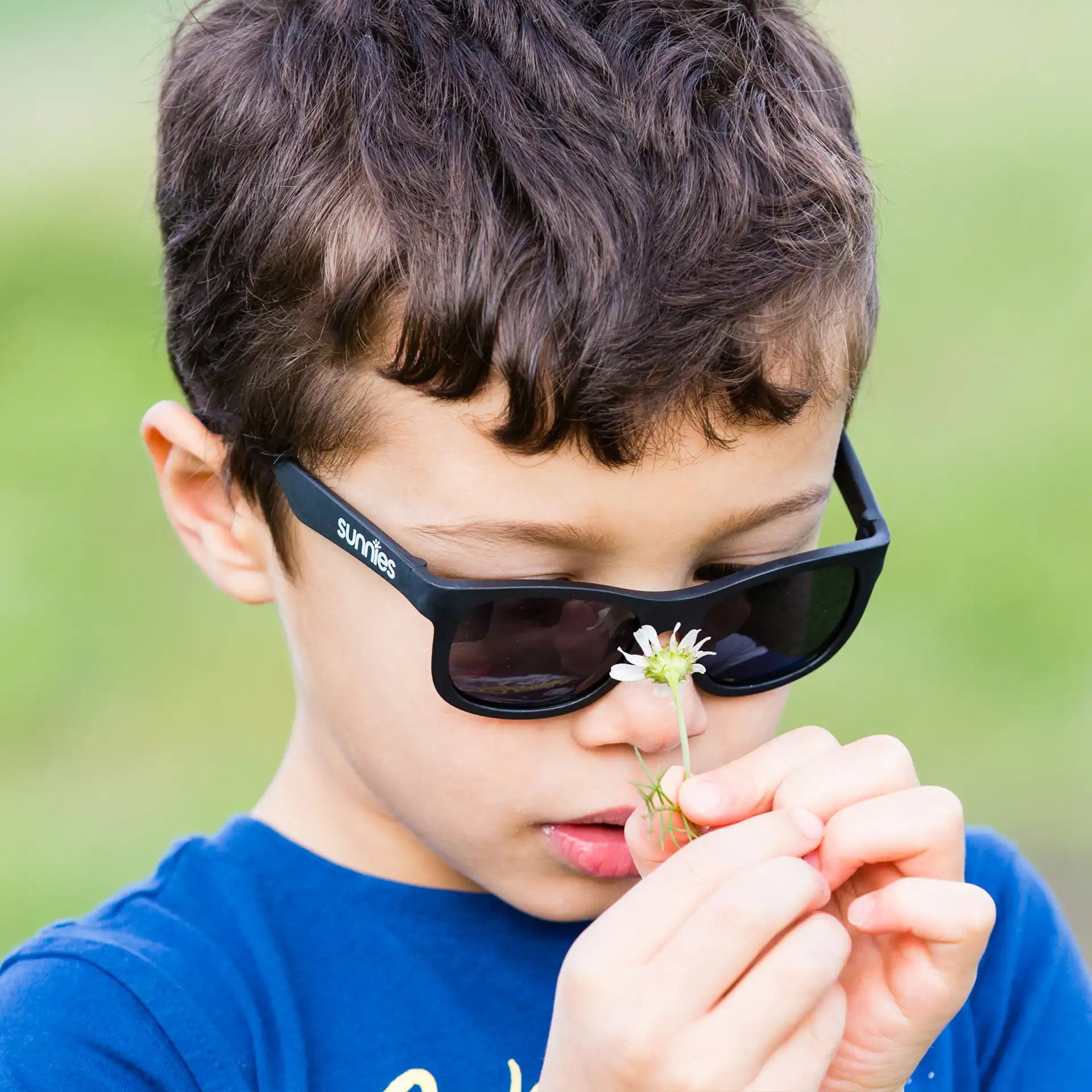 Boy wearing black sunglasses holding a flower